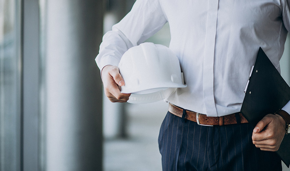 Homme portant un bloc note dans une main et un casque de chantier dans l'autre